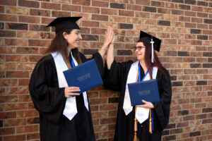 Two students in caps and gowns high-fiving
